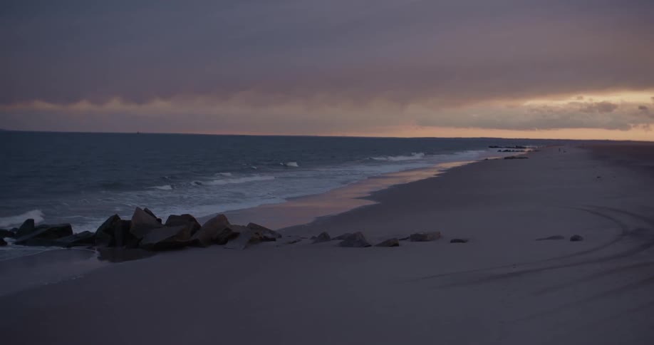 Waves gently lap an empty beach at sunset