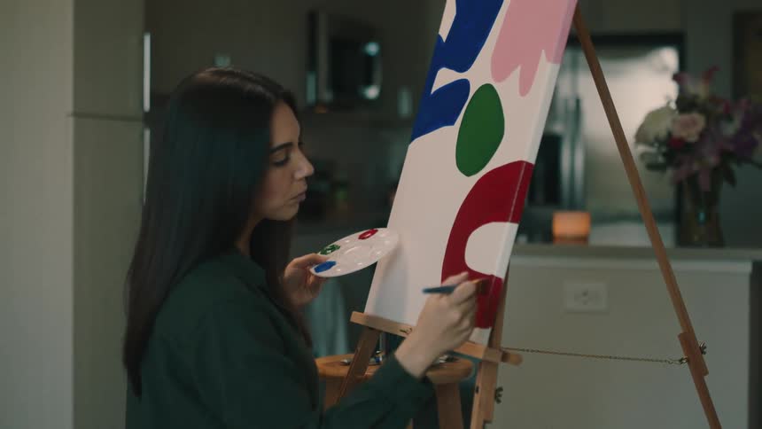 Woman holding a paint palette and painting a picture