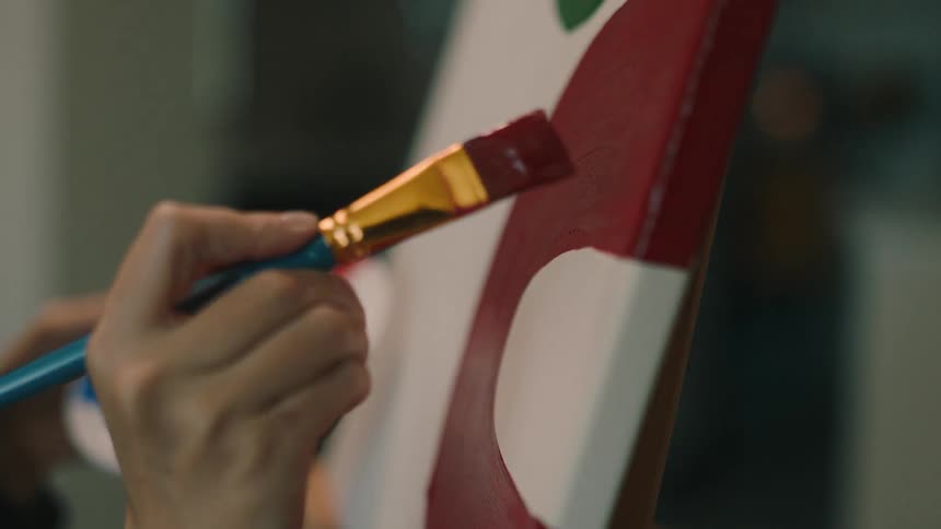 A clip of a hand holding a brush paint and painting on a board