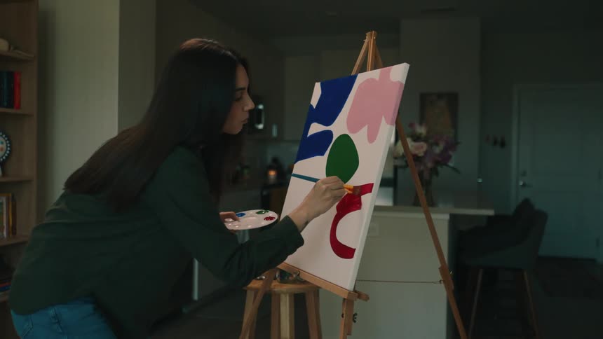 Woman painting a canvas with a brush with red paint