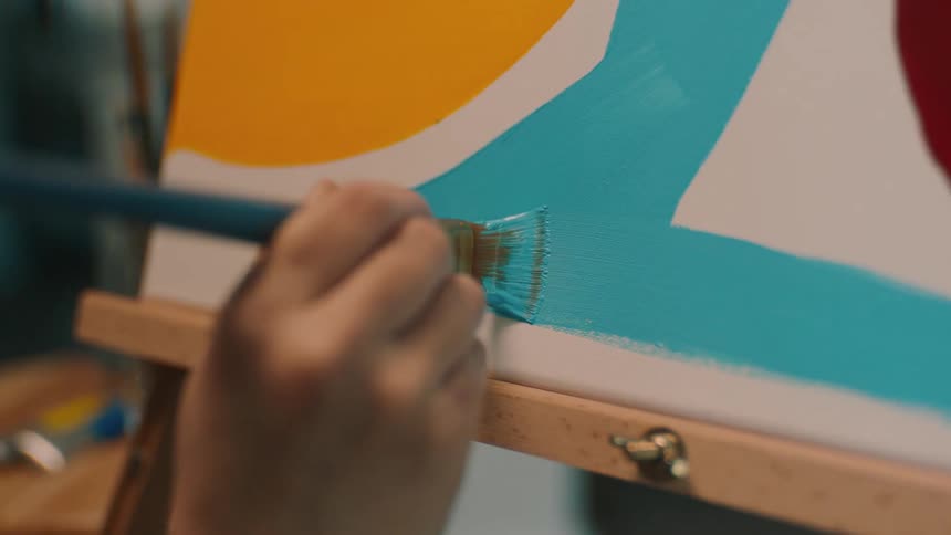 A female is painting blue paint on a board with a brush