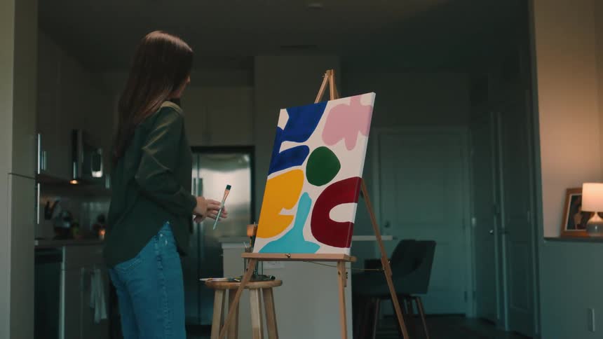 A woman is painting on the canvas