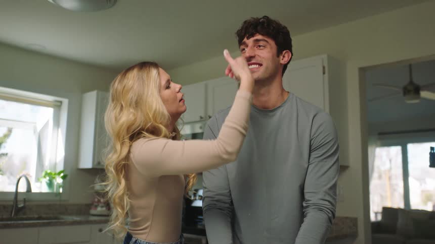 Smiling couple in the kitchen playing with a cream