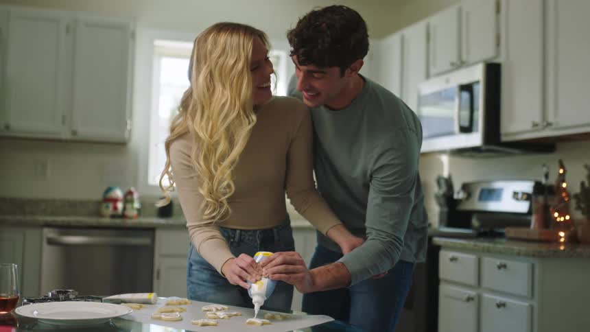 Smiling couple together putting cream on top of a cookie