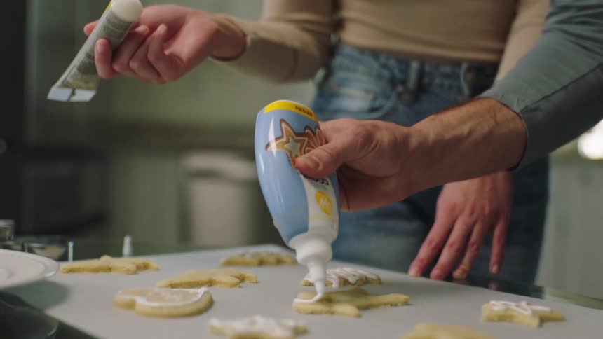 Couple putting cream on top of cookies