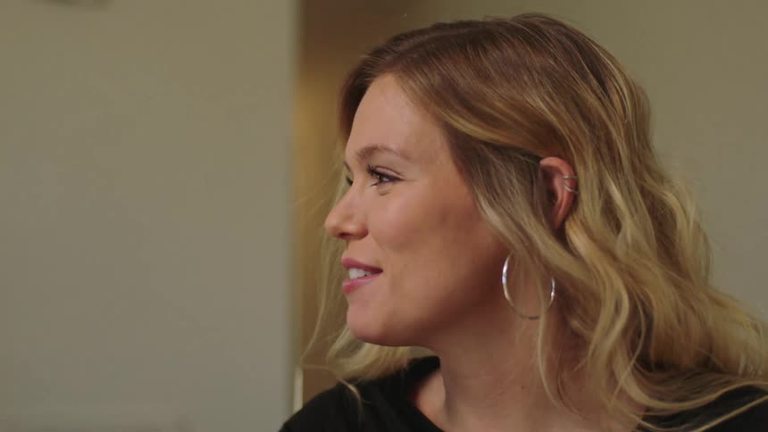 Woman smiles while turning her had to the side and talking