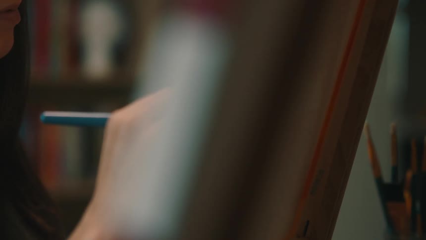 Closeup on a woman painting a canvas