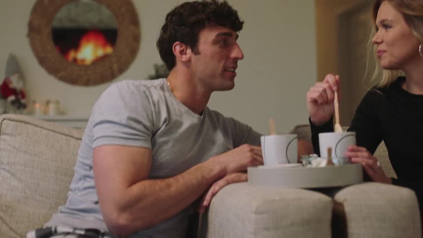 Two people are drinking out of mugs indoors