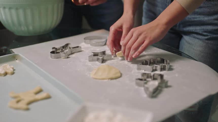 A persons hands preparing cookies in a starshaped pan and then placing them in a container