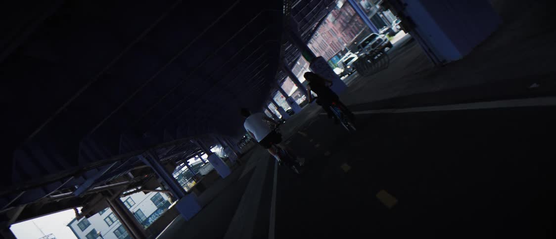 Two people cycling under an overpass