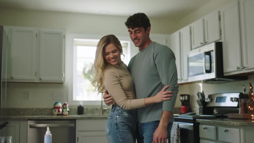 Two people hugging and kissing in a kitchen