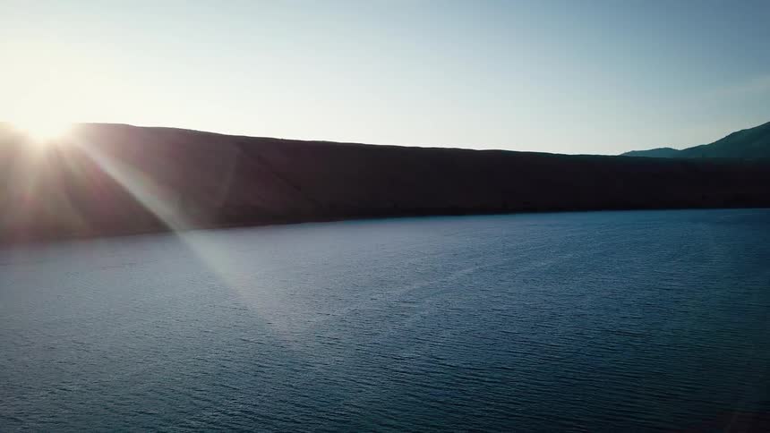 Panorama of the sea at the edge of mountains with sunrise on the horizon