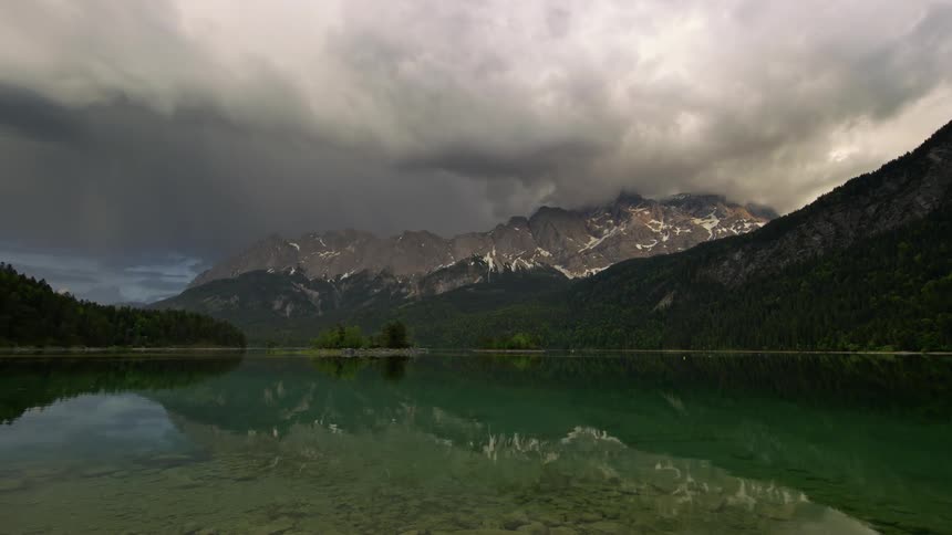 Landscape of a lake reflecting the surrounding mountains on a cloudy day