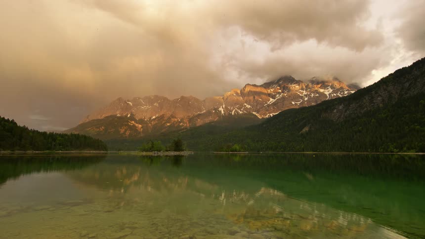 A mountain range and forest serves as a backdrop for a lake