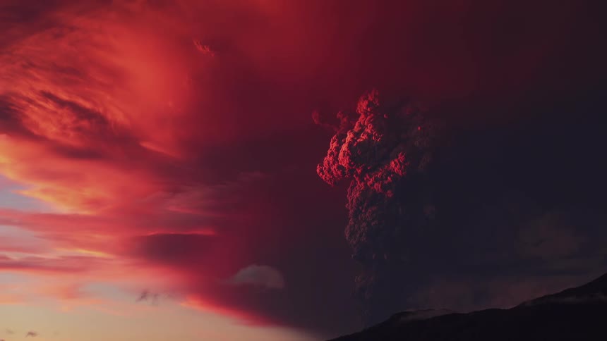 Panorama of volcanic smoke rising against a reddened sky