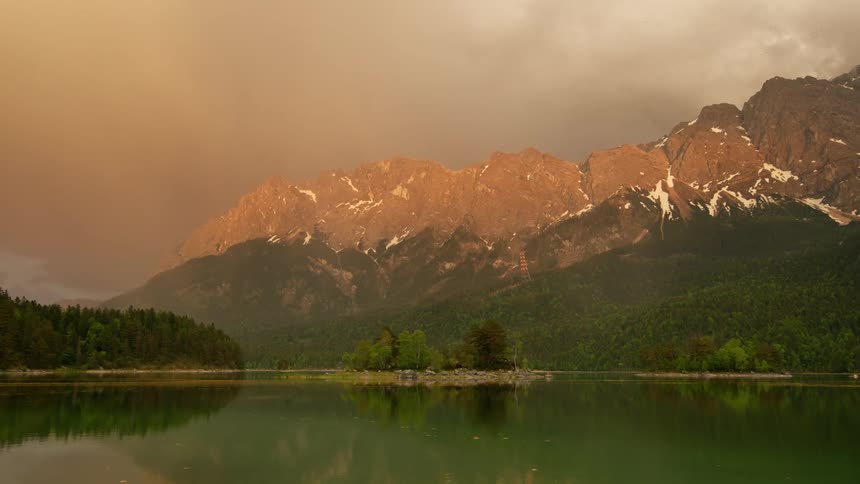 A tall mountain range sits next to a lake