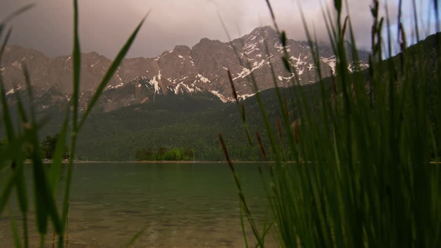 Panorama of a lake amidst a mountain range under a cloudy sky