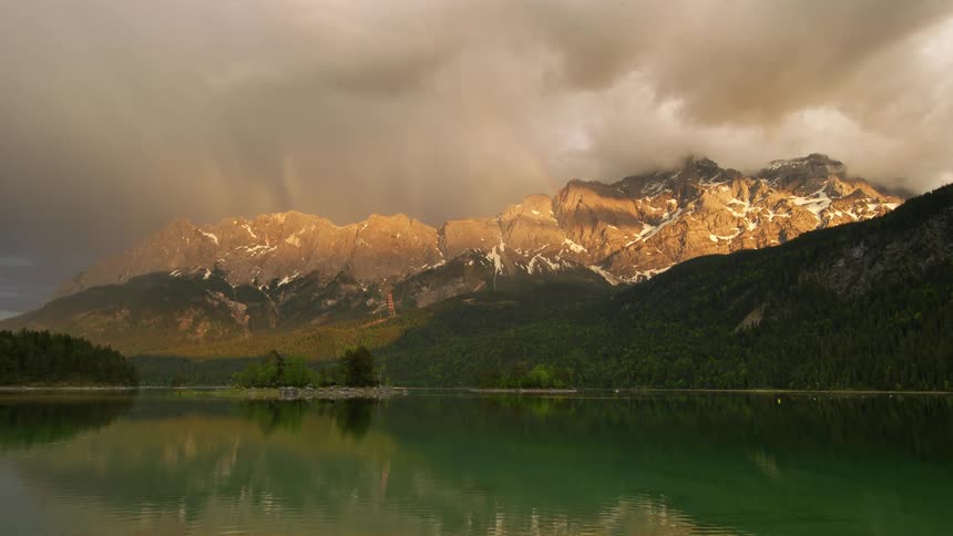 Reflective lake surrounded by mountain range under grey clouds