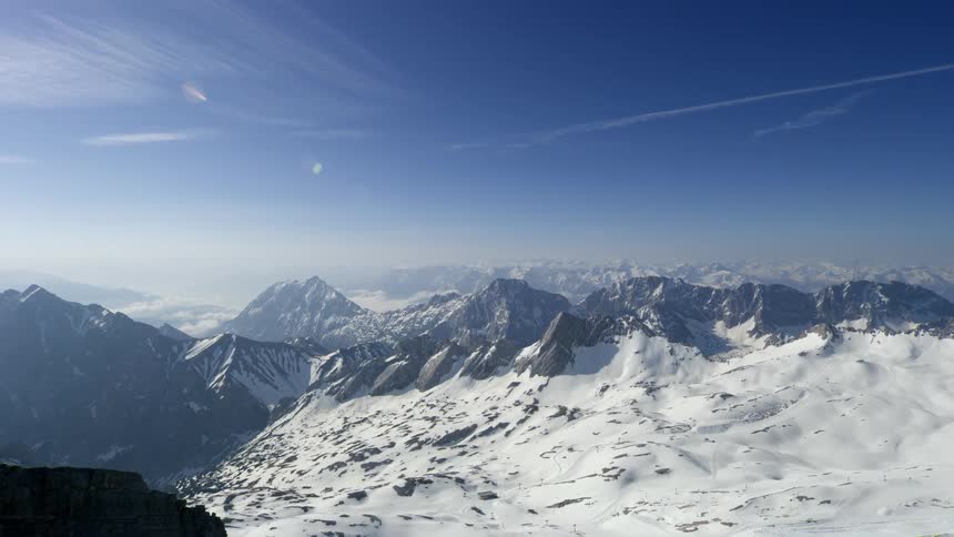Snow covered mountain range under partly cloudy blue skies
