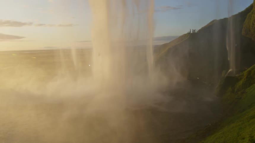 Water flowing down waterfall creates heavy mist upon hitting pool at base of cliff