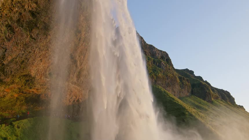 A serene scene of a large waterfall and a lake under a clear sky