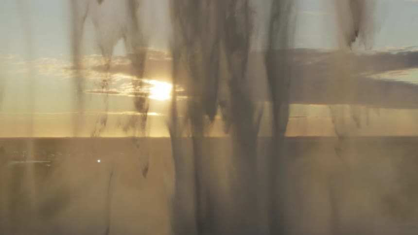 Waterfall cascading in slow motion with the sun on the horizon