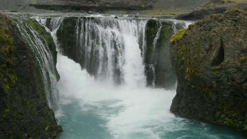 A large waterfall spills into a river