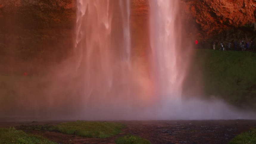 Waterfall spills into red rock cave