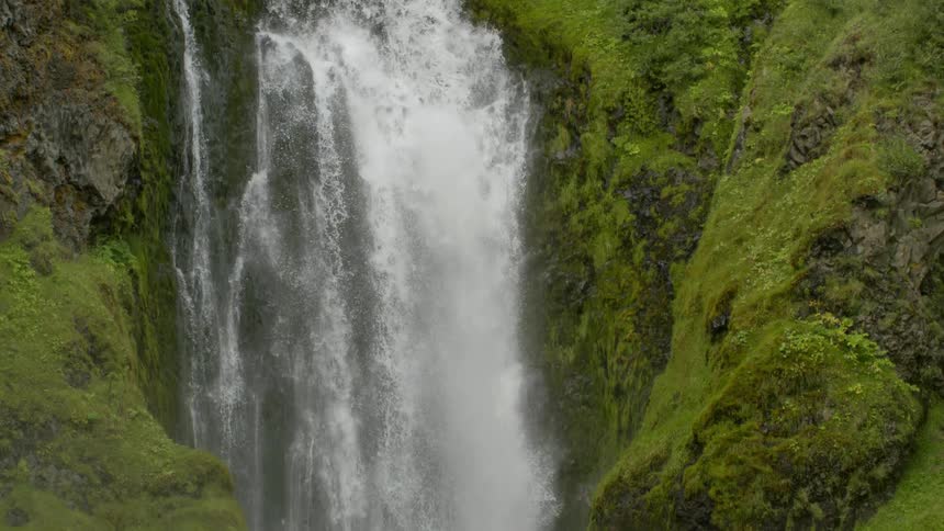 Whitewater waterfall spills into river below green vegetation