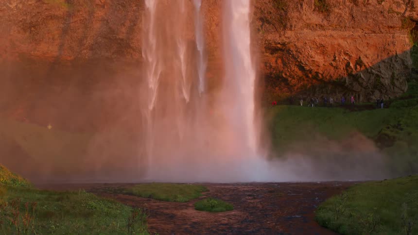 A dual waterfall flows down a cliff into a river