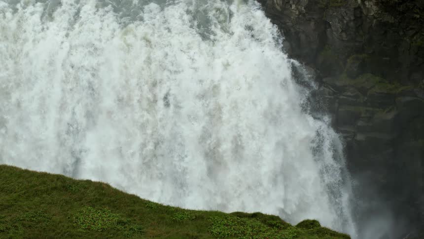 Large waterfall flows into canyon topped by grassland