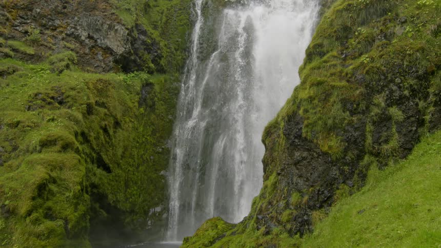 A waterfall on a mossy mountain during a cloudy day