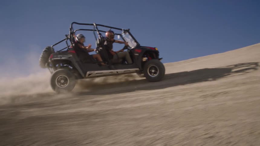 Offroad buggy with four people performing maneuvers in desert hills