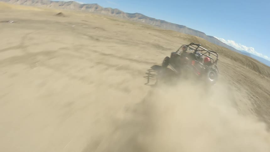 Four guys race across a desert in a buggy