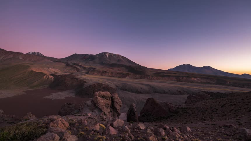 Shadows flow across arid mountainous terrain as night falls
