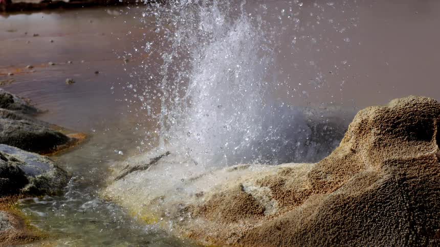 Hot water with steam emanating from a small rocky crater