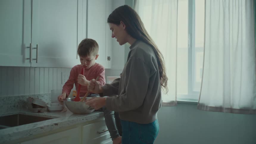 A mother and son mix food in a bowl