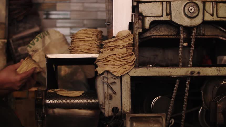 Hand of a person collecting small strips of dough from a machine