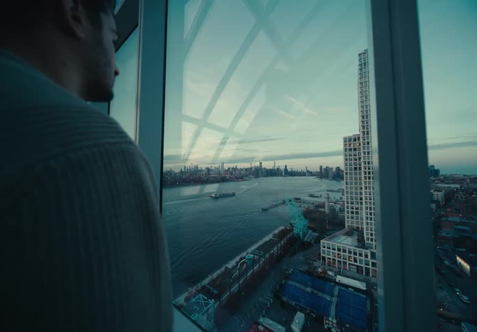 A man on top of a building observes the city at dusk