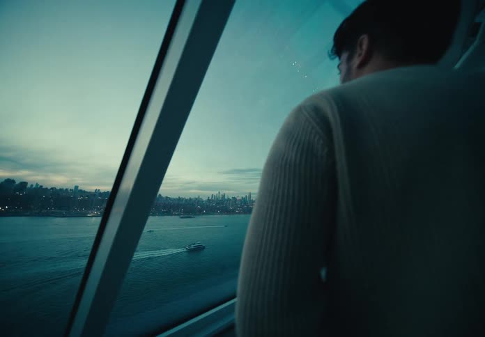 Man on a glass terrace overlooking the sea in a metropolis under a darkened sky