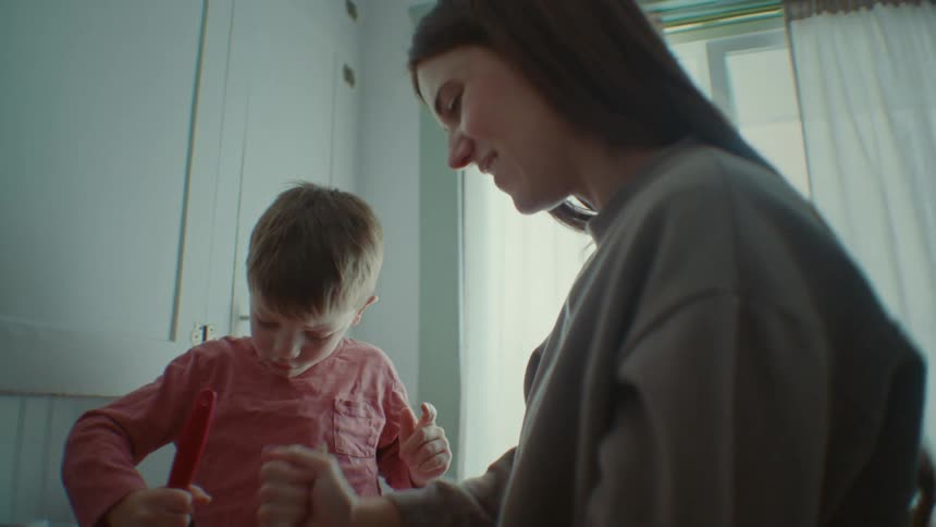 Son helping his mother cook with a spatula in the kitchen