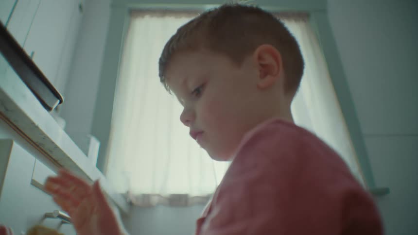 A boy pats dough and puts it on a pan