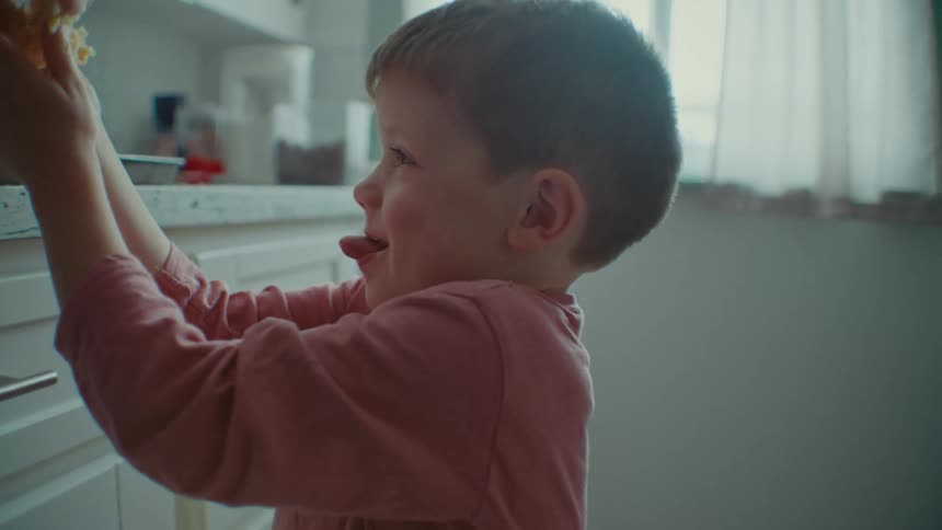 A little boy puts cookie dough on a pan