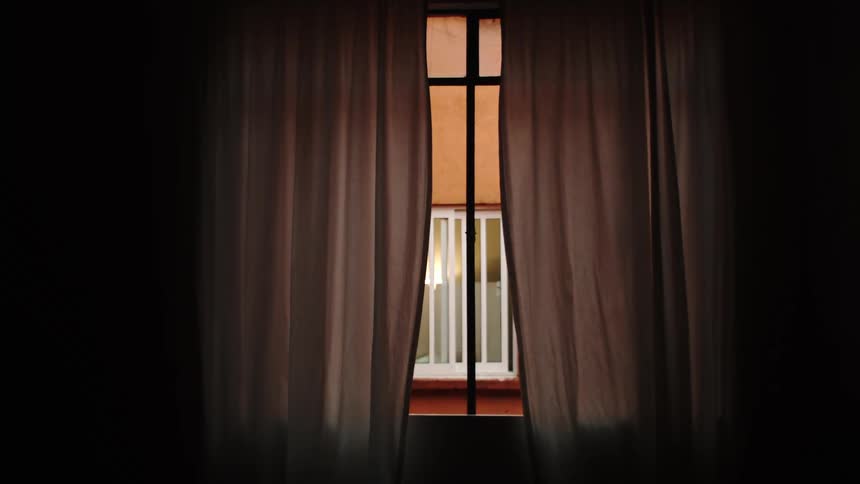 Window ajar in a room with gray curtains
