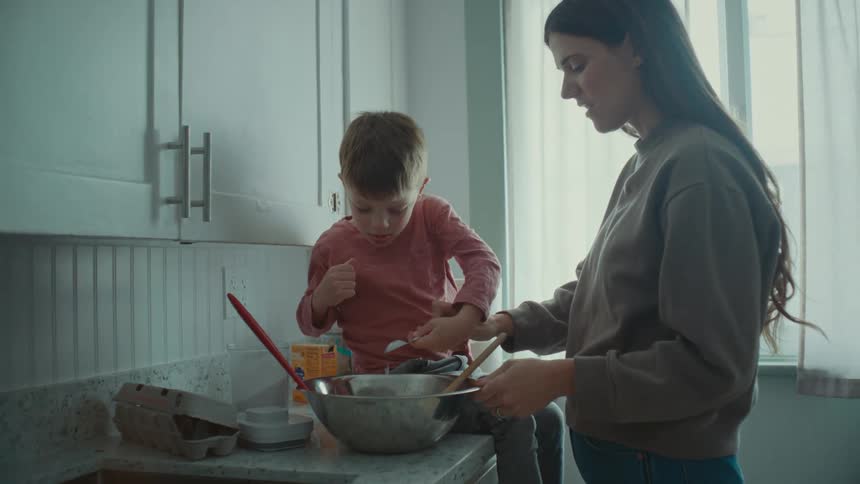 A mother and son are cooking in the kitchen