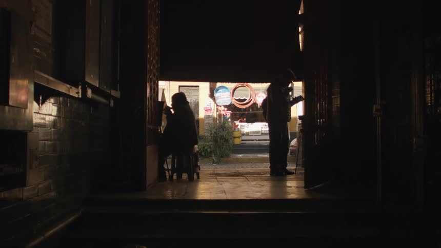 Two people silhouetted against road eat as a vehicle passes
