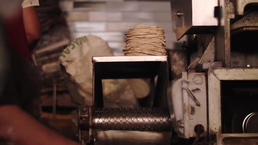 An employee removes tortillas from a machine