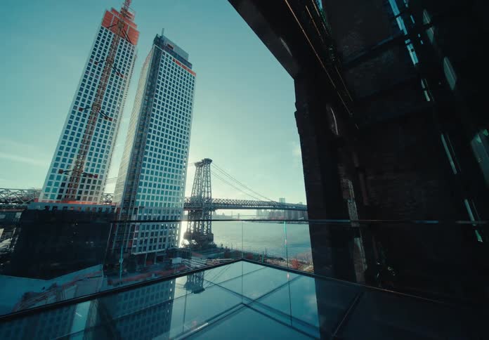 Two towers stand together in a city shown from a glass covered enclosure