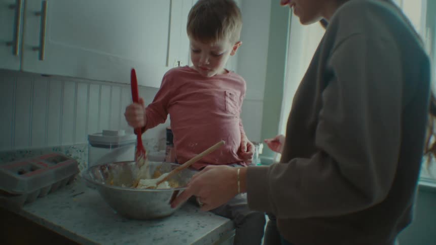 A mother and son are cooking in the kitchen