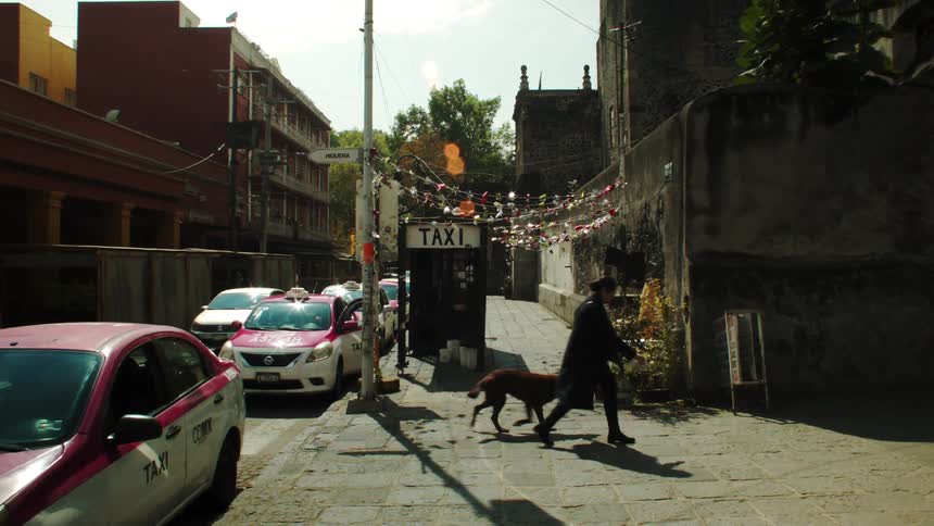 Woman crosses street passing by cabstand